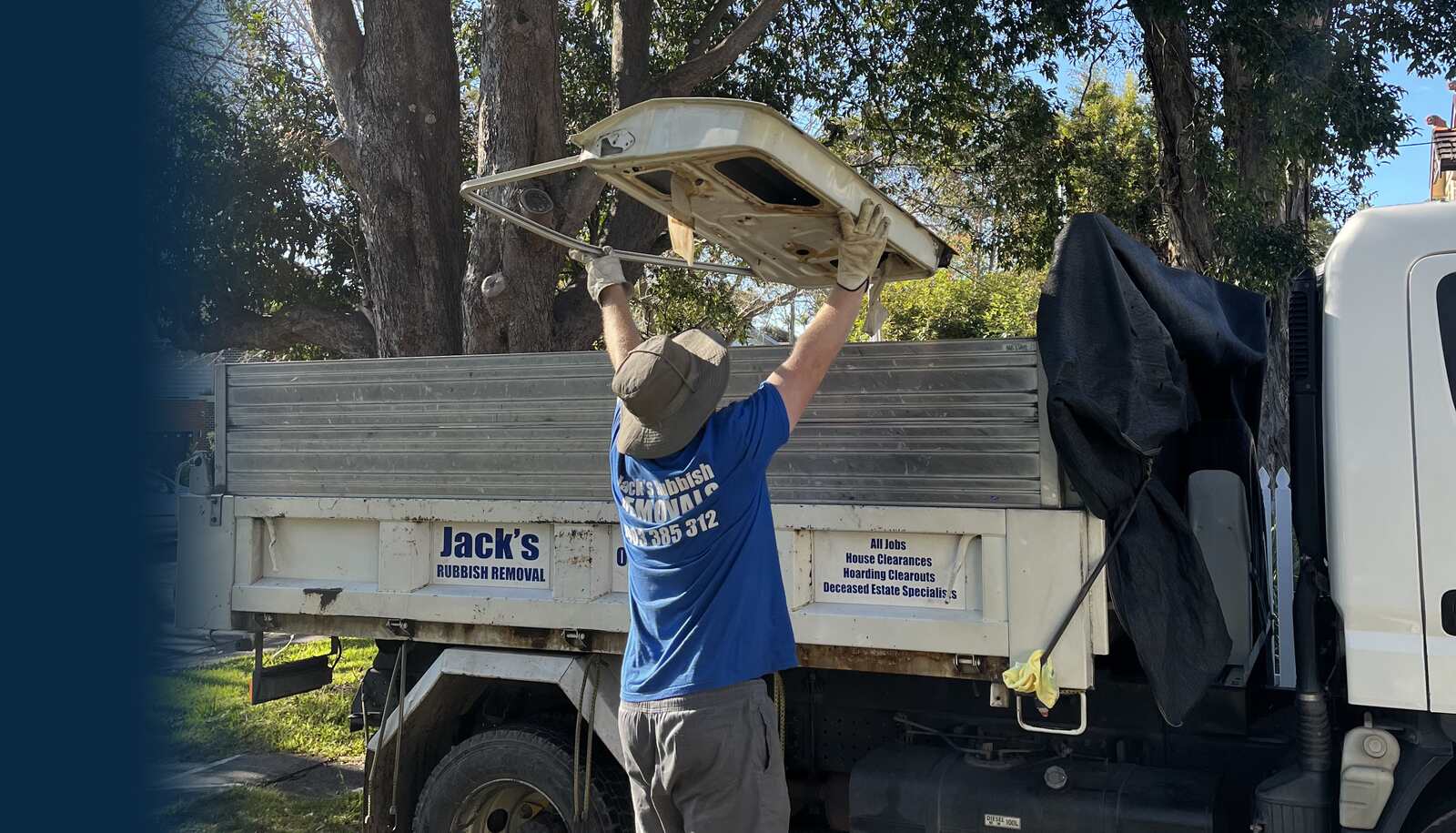 A Jack's Rubbish crew member loading an old benchtop into the branded tipper truck